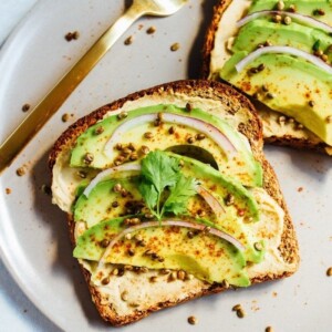 Avocado hummus toast with hemp seeds on a plate with a fork.