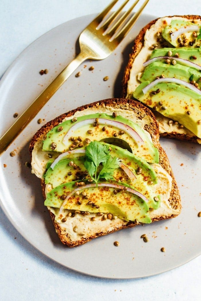 Hummus avocado toast makes for a quick and easy breakfast or snack idea. Load up each slice with red onion, cilantro and toasted hemp seeds for extra flavor and crunch. 