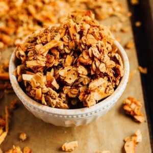 Bowl of granola on a baking sheet with parchment.