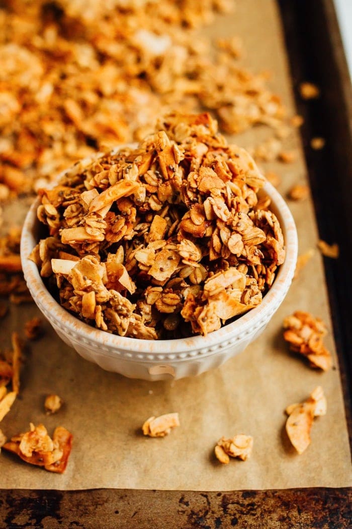 Bowl of granola on a baking sheet with parchment.