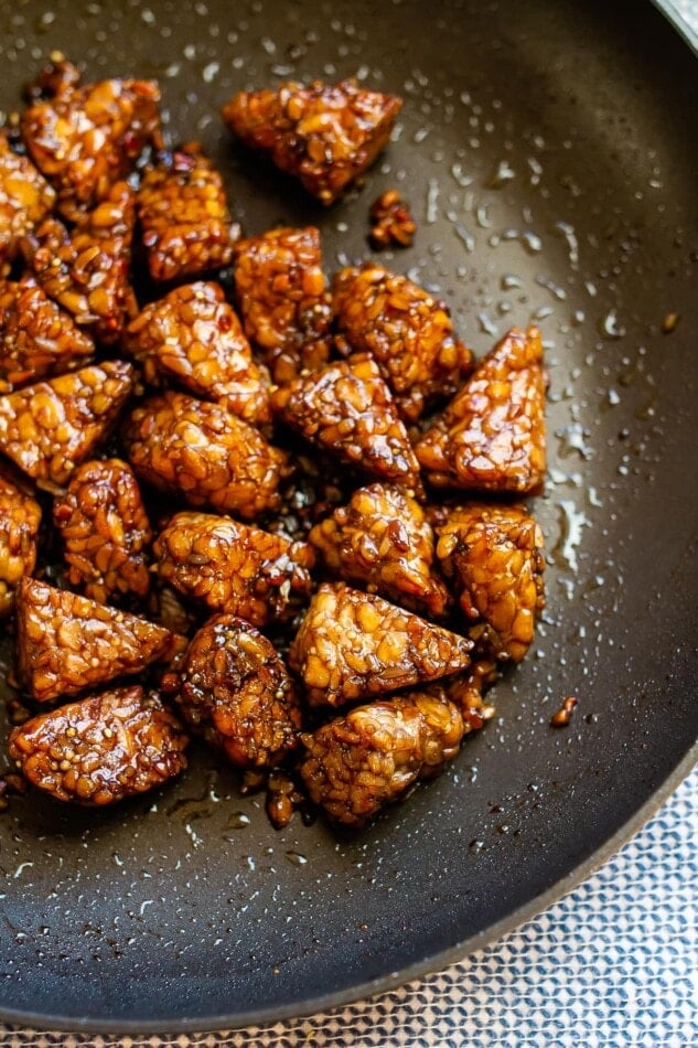 Marinated tempeh that's finished cooking in a large skillet.