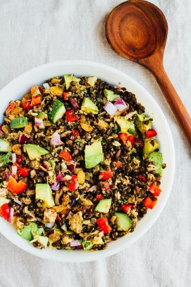 Lentil tuna salad with chopped vegetables and a wooden spoon.