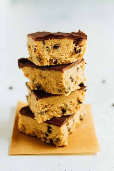 Stack of four no bake cookie dough bars topped with chocolate.