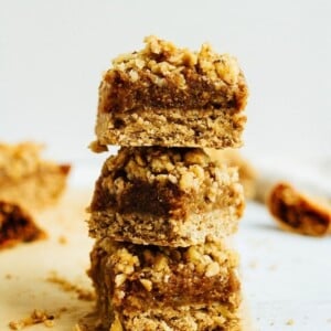 Stack of three fig crumble bars on parchment.