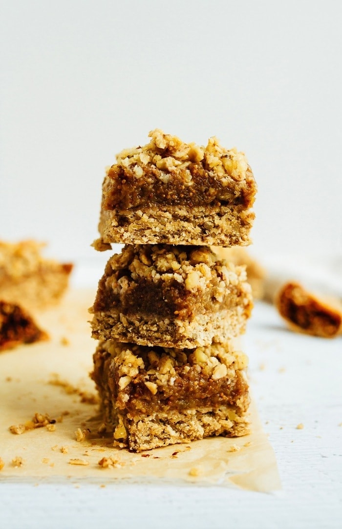 Wholesome Fig Jam Crumble Bars you can feel good about enjoying for breakfast, a snack or dessert. They’re loaded with healthy fats and naturally sweetened. Stack of three fig crumble bars on parchment.