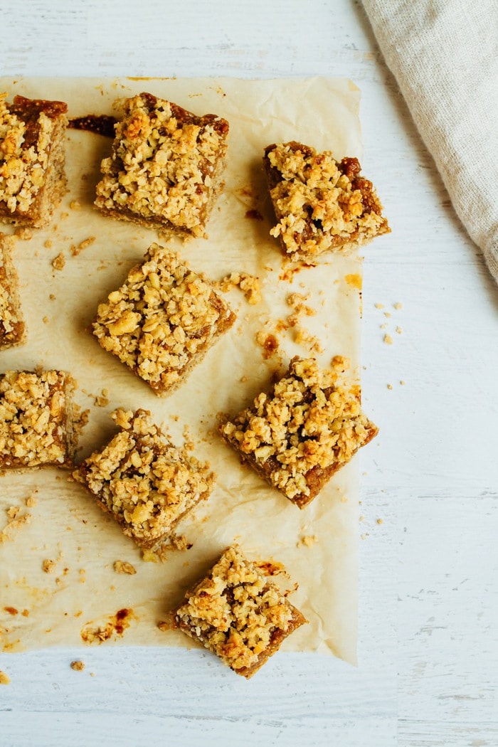 Wholesome Fig Jam Crumble Bars you can feel good about enjoying for breakfast, a snack or dessert. They’re loaded with healthy fats and naturally sweetened. A few fig crumble bars on parchment.