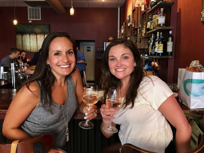 Two women smiling with rose at a bar.