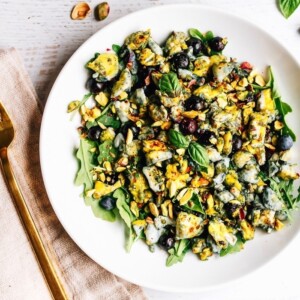 Blueberry Eggs Breakfast Salad with basil and pistachios on a plate.