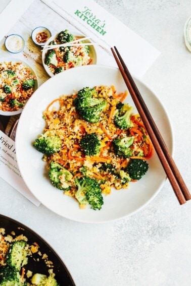 Cauliflower rice with carrots, corn, and broccoli. Chopsticks sitting on the plate.