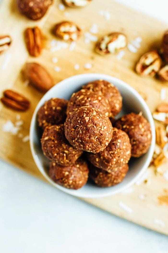 Overhead shot of German Chocolate Energy Bites with Pecans served in a white bowl on wood cutting board.