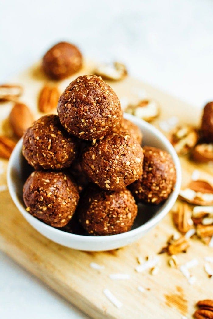 German Chocolate Energy Bites with Pecans served in a white bowl on wood cutting board.