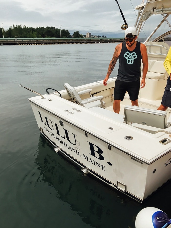 The back of the Lulu B boat on the water. Man with a sleeve tattoo on the boat.