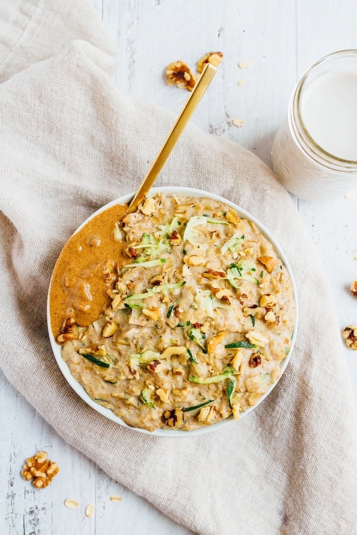 Bowl of zucchini bread oatmeal topped with walnuts and almond butter.