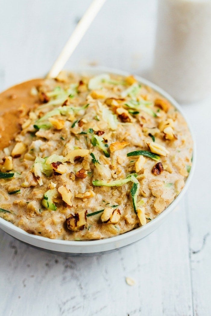 Bowl of zucchini bread oatmeal topped with walnuts and almond butter.