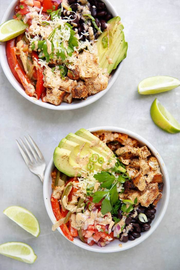 Bowl of copycat chipotle chicken burrito bowls with avocado and cilantro topping.