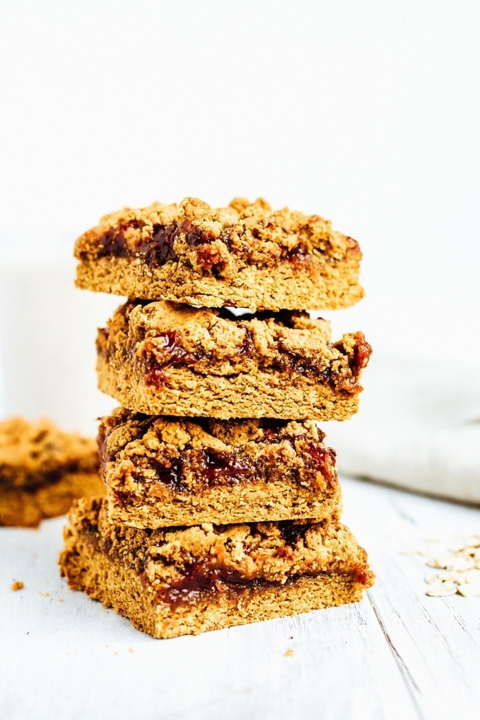 Stack of four pb&j bars. Bars filled with jam, topped with peanut butter crumble.