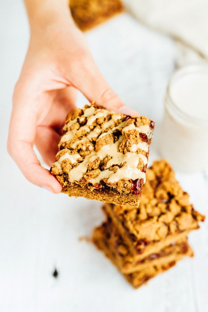 Hand holding a Peanut Butter and Jelly Bar. A stack of bars is in the background.