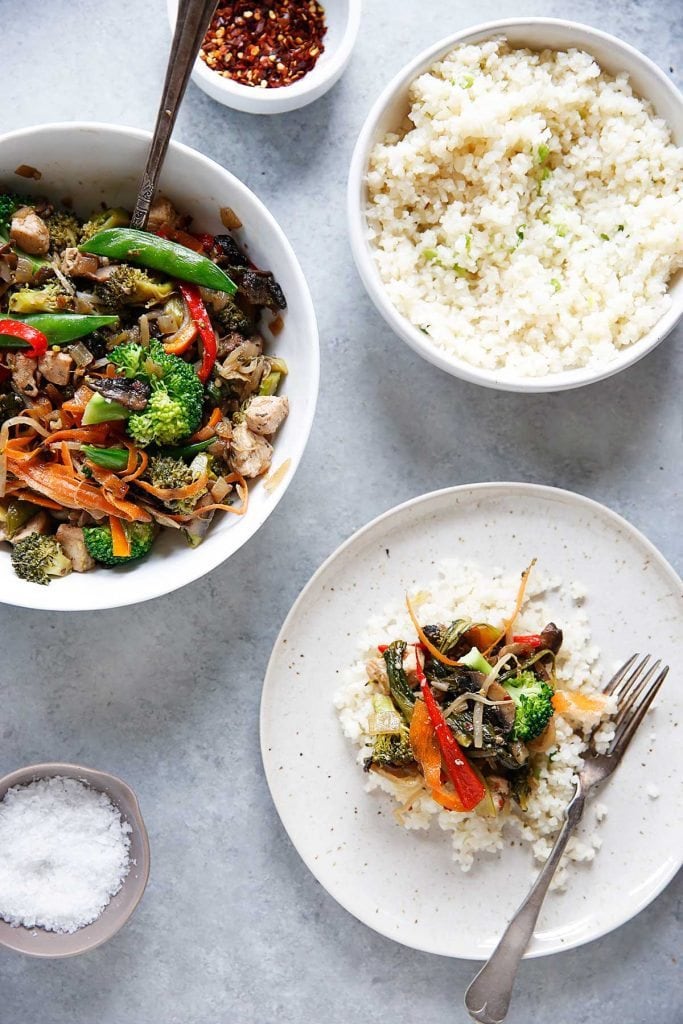 Overhead shot of three bowls full of stir fry with garlic scallion cauliflower rice.