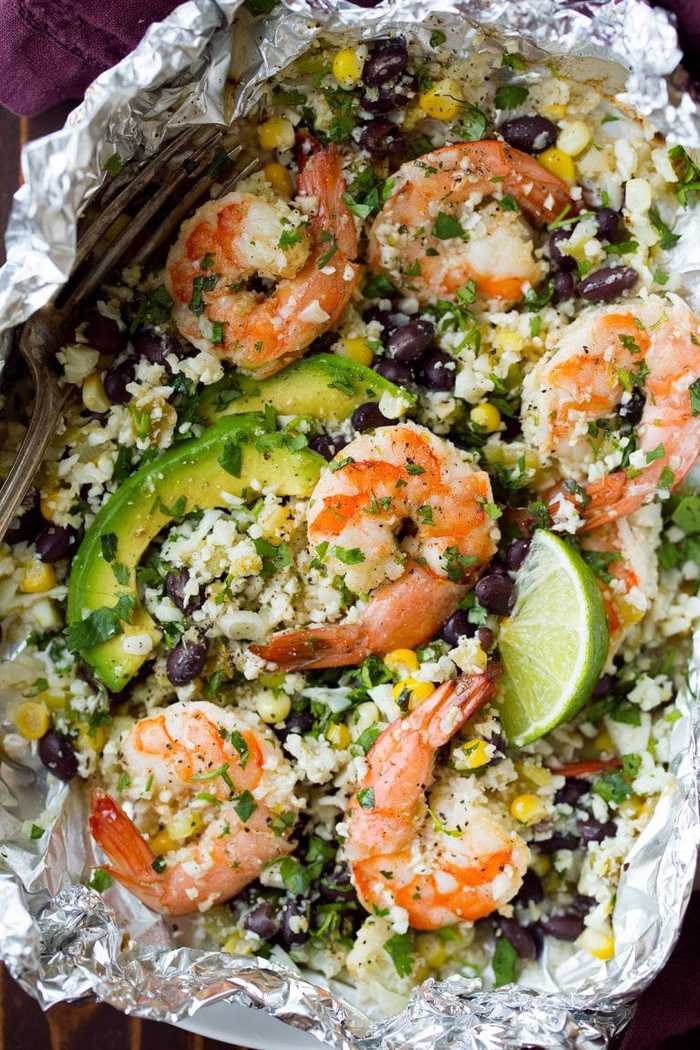 Close up shot of lime shrimp and cauliflower rice in a tin foil packet.