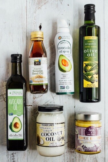 Bottles of avocado oil, sesame seed oil, coconut oil, oilive oil, ghee, and avocado oil spray.
