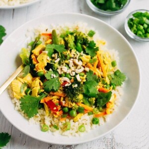 Tuna curry with vegetables over cauliflower rice in a white bowl, with small bowls of cilantro and green onion on the side.