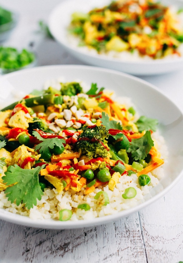 Tuna curry with cauliflower rice bowl topped with green veggies, cilantro and a drizzle of sriracha.