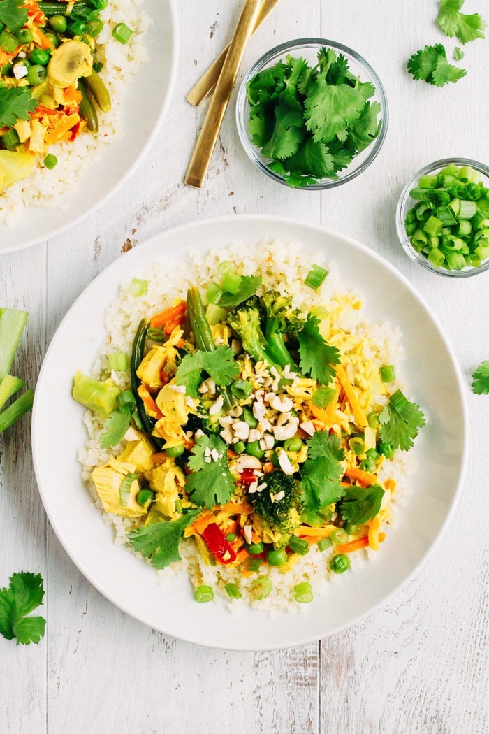 Tuna Curry Bowl with Cauliflower Rice, topped with cilantro. Fold in the bowl. Bowl next to smaller bowls of chopped green onions and cilantro.