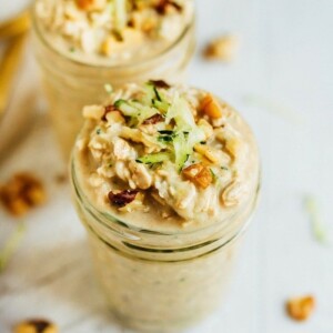 Two cups with zucchini bread overnight oats topped with grated zucchini and walnuts.