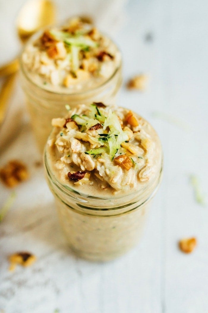 Zucchini bread overnight oats in small mason jars with walnuts and grated zucchini on top. 