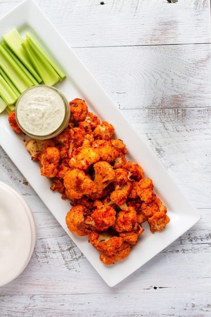 Buffalo Cauliflower wings. A healthy game day recipe. Served with celery sticks and a healthy dipping sauce.