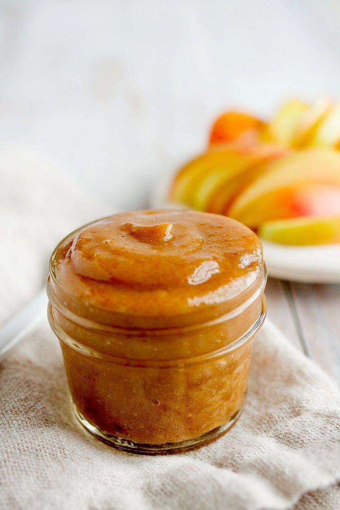 A small glass jar overflowing with date caramel sauce.