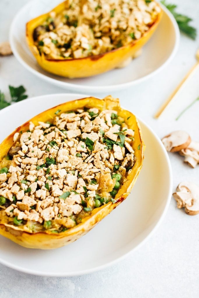 Two spaghetti squash tuna casserole boats on white plates.