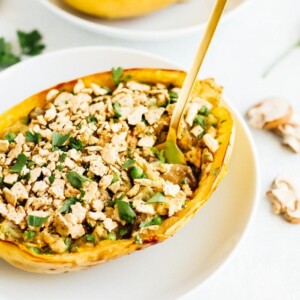 Two spaghetti squash tuna casserole boats on white plates.