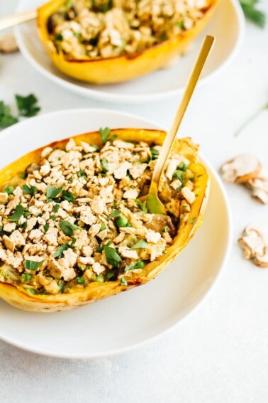 Two spaghetti squash tuna casserole boats on white plates.