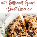 Bowl of wild rice stuffing filled with cherries and butternut squash. Serving spoon is in the bowl, and a sprig of thyme on top. Text reads "wild rice stuffing with butternut squash and sweet cherries"