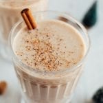 Dairy free egg nog in a glass with cinnamon stick.