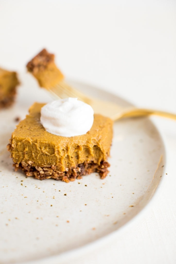 No Bake Pumpkin Pie Bar on a plate with a fork that has taken a bite out of it.