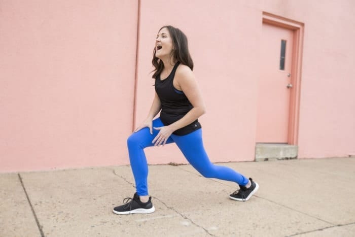 True Life: I’m an Influencer // Eating Bird Food Woman laughing and lunging in activewear on a sidewalk.