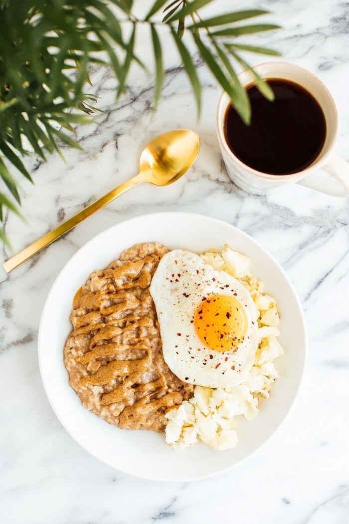 Sweet + Savory Egg and Oatmeal Combo Bowl in a white bowl served with gold spoon and cup of coffee.