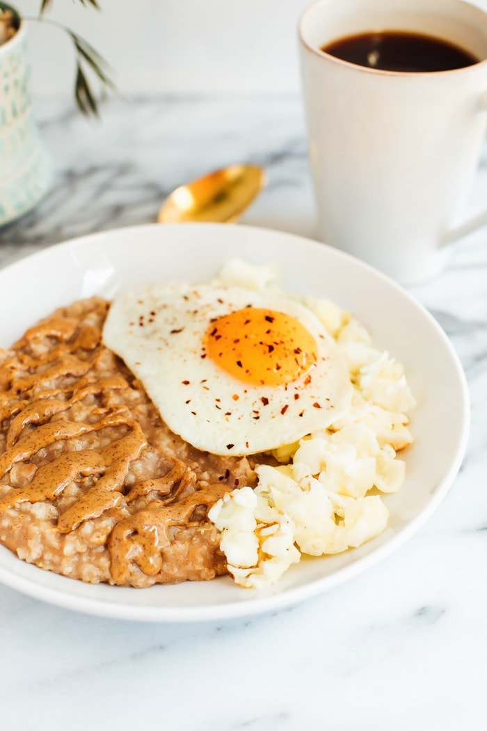 Sweet + Savory Egg and Oatmeal Combo Bowl in a white bowl served with gold spoon and cup of coffee.