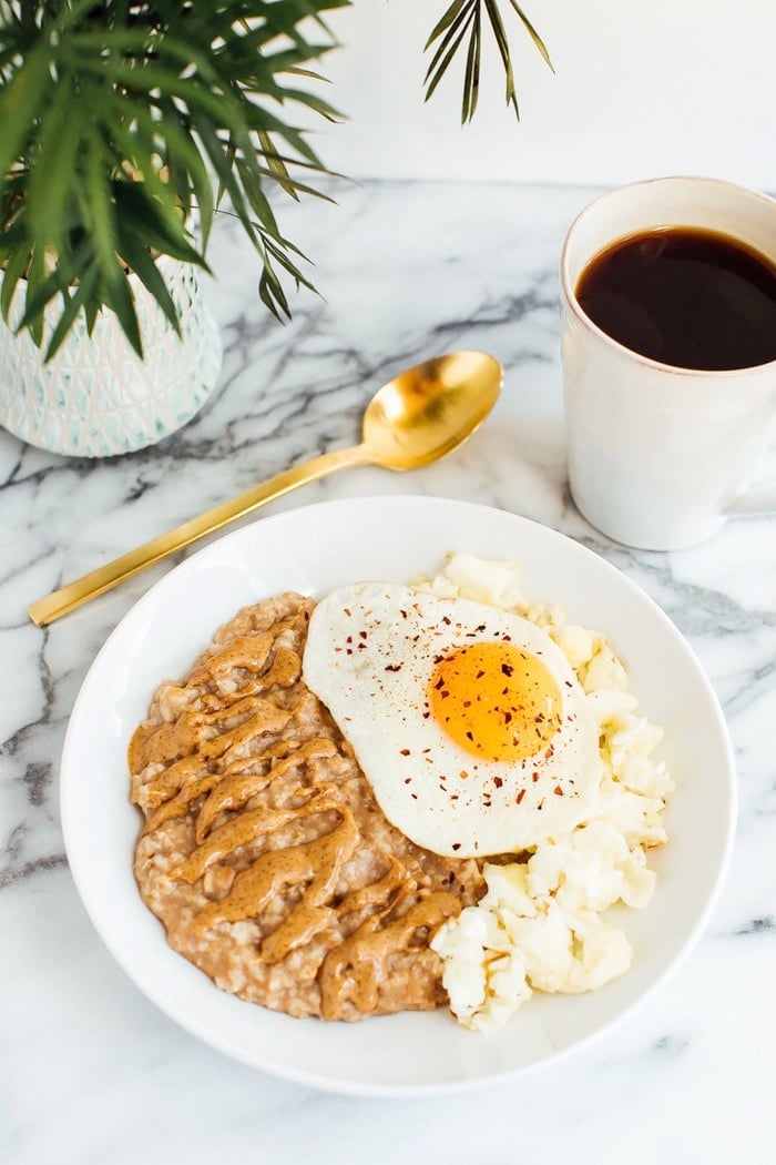 Sweet + Savory Egg and Oatmeal Combo Bowl in a white bowl served with gold spoon and cup of coffee.
