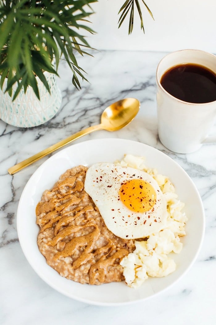 Sweet + Savory Egg and Oatmeal Combo Bowl in a white bowl served with gold spoon and cup of coffee.