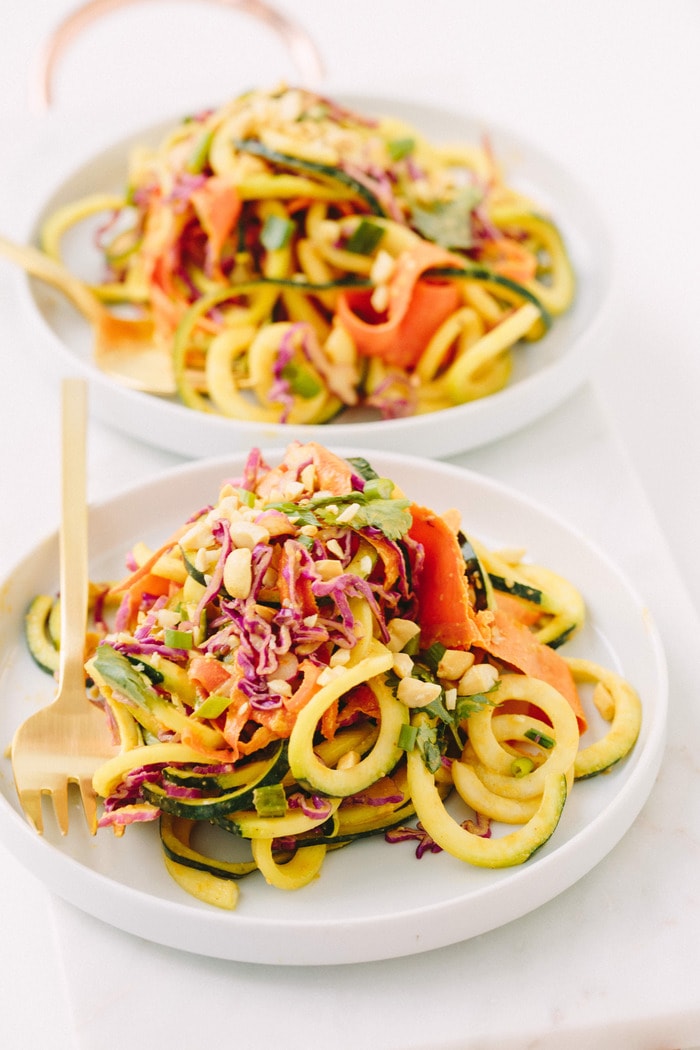 Close up shot of Thai zucchini noodles on a shallow rimmed bowl with a gold fork.