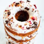 Stack of baked almond flour donuts with rose petals and dark chocolate.