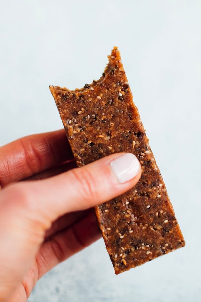 Hand holding a chia bar with bite taken out of it.