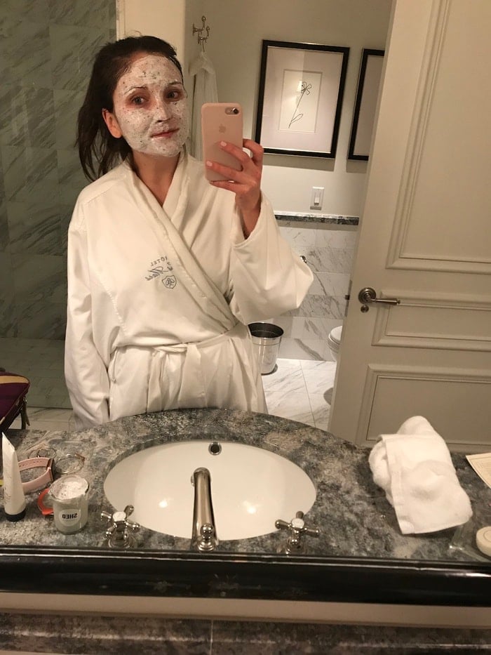 Woman wearing a face mask and a robe in a bathroom.
