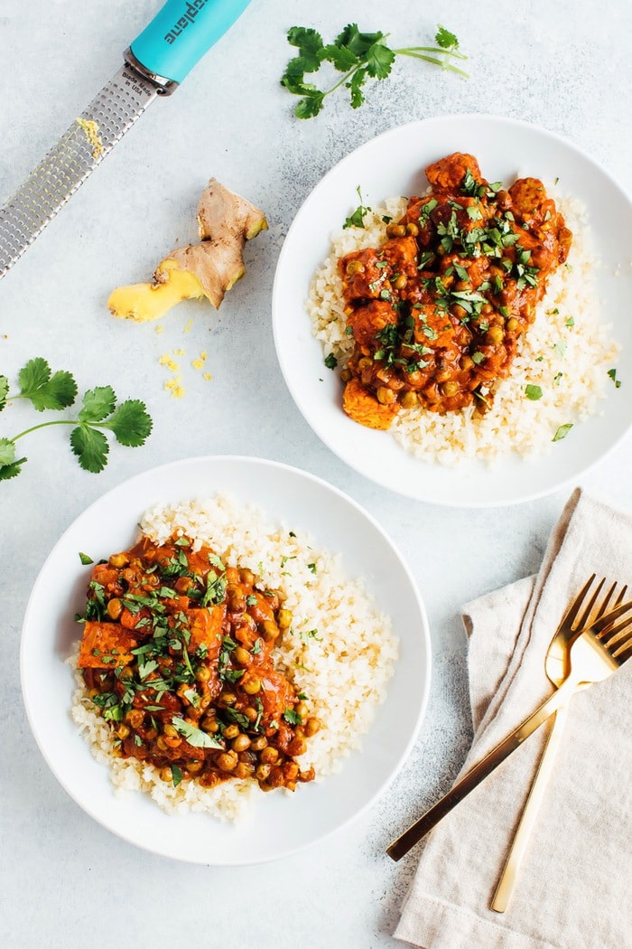 Two bowls of vegan tempeh tikka masala with microplane and forks.