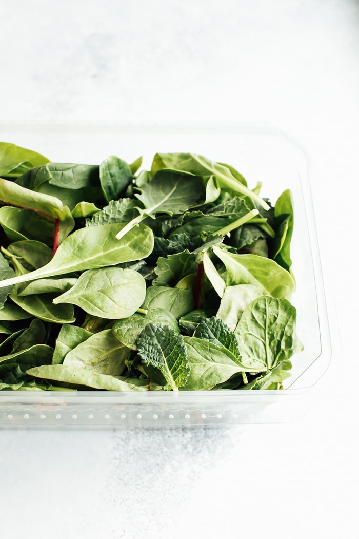 A plastic clam-shell container with baby greens. 