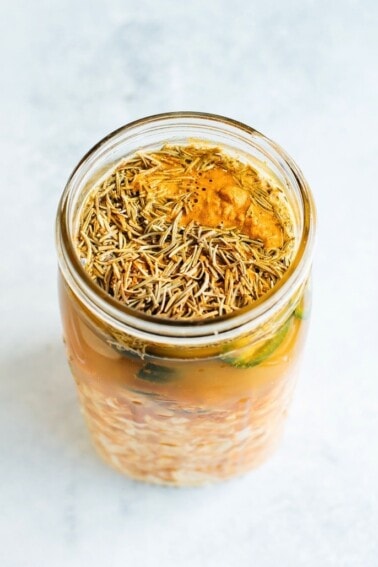 Adding all the roots, herbs and fresh vegetables into a mason jar for fire cider.