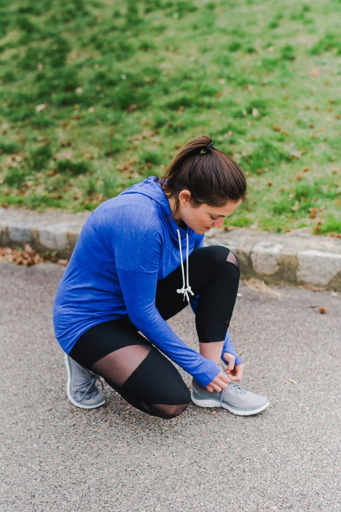 Woman wearing workout gear tying shoe 